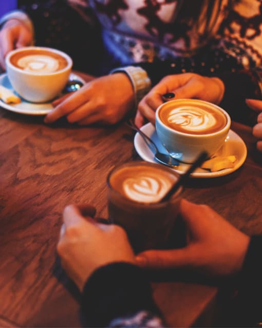 Two cups of coffee with latte art on a wooden table.