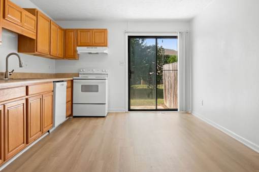 A kitchen with wooden cabinets and a white stove top oven.