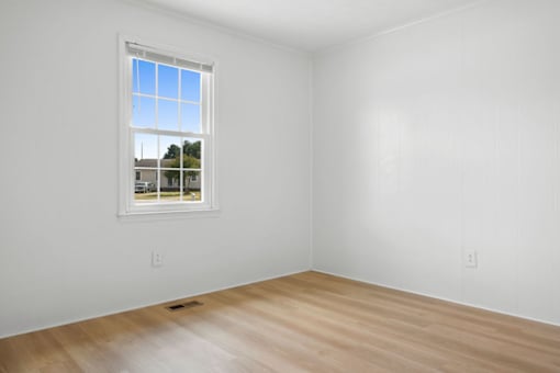 A room with a window and wooden floor.