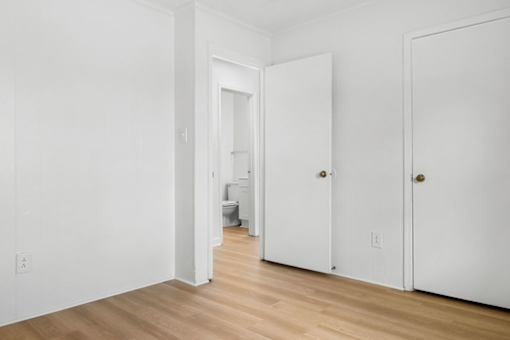 A white room with a doorway leading to a bathroom.