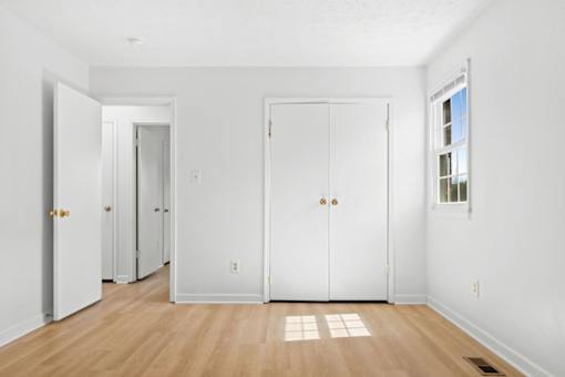 A white room with a wooden floor and three doors.
