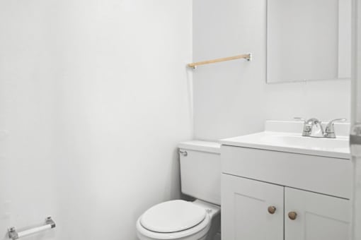 A white bathroom with a toilet, sink, and mirror.