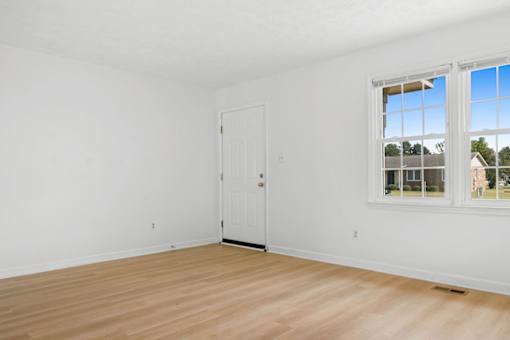 A room with a white door and a window with a view of a building outside.