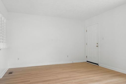 A room with a white door and wooden floor.