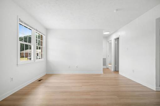 A large empty room with wooden floors and white walls.