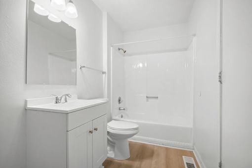 A white bathroom with a toilet, sink, and mirror.