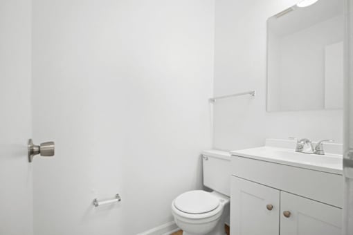 A white bathroom with a toilet, sink, and mirror.