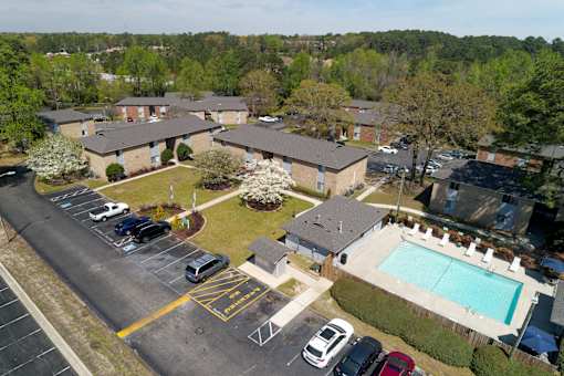 A parking lot with a pool and apartment buildings in the background.