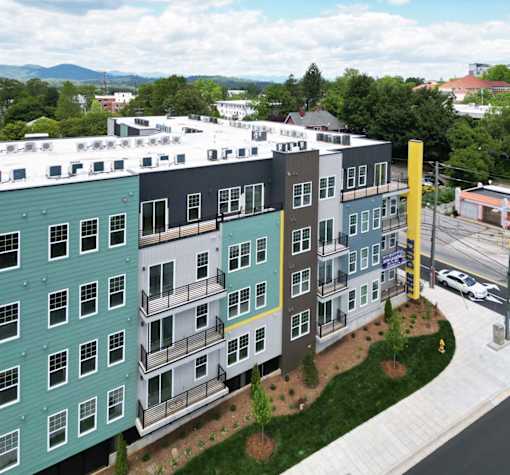 A modern apartment complex with balconies and a view of the mountains in the distance.