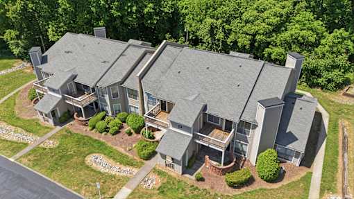A large house with a grey roof and a driveway in front.