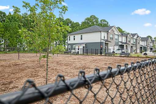 A chain link fence in front of a row of houses.