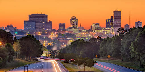 A cityscape at dusk with a road leading into the distance.