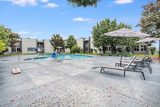 A pool area with a table and chairs and a building in the background.