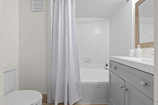 A white bathroom with a toilet, sink, and shower.