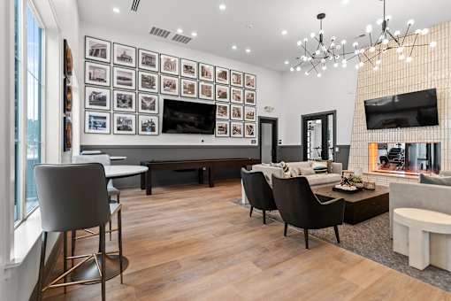 A modern living room with a large TV and a long table with chairs.