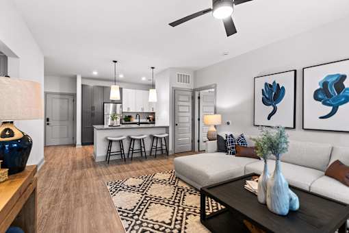 A modern living room with a white sofa, a coffee table, and a ceiling fan.