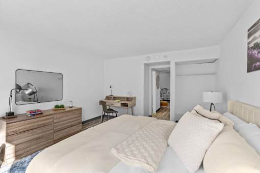 A bedroom with a large bed and a desk with a chair.