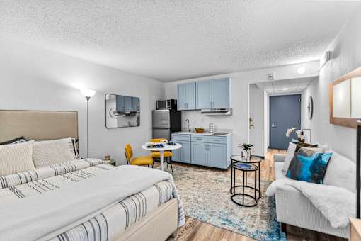 A bedroom with a bed, a couch, and a small kitchenette.