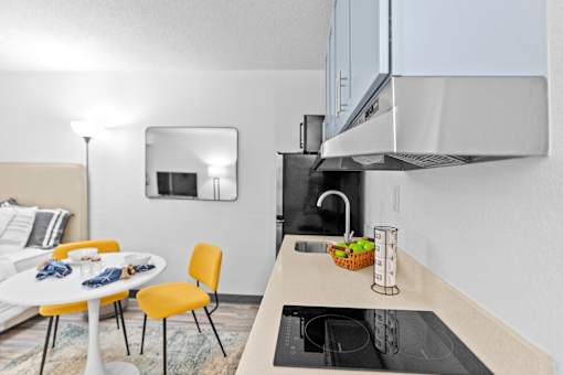 A modern kitchen with a white table and yellow chairs.