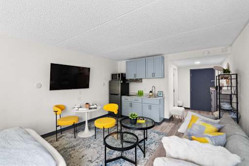 A living room with a grey couch, yellow chairs, and a black table.