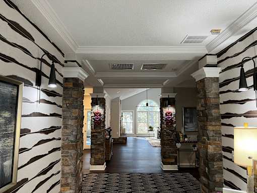 A hallway with a striped wallpaper design and stone pillars.