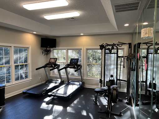 A gym with treadmills, weights, and a television.