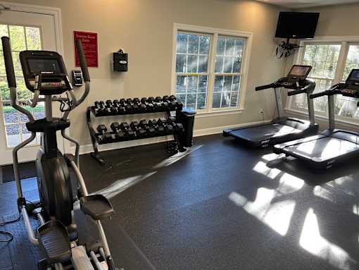 A gym with treadmills, elliptical machines, and dumbbells.