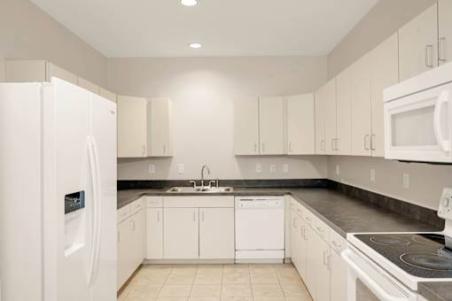 A white kitchen with a refrigerator on the left.