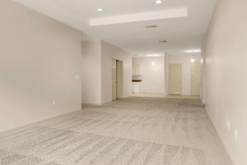A spacious hallway with a carpeted floor and white walls.
