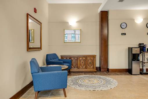 A waiting area with blue chairs and a wooden cabinet.