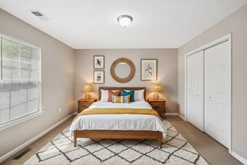 A bedroom with a bed, nightstands, and a rug.