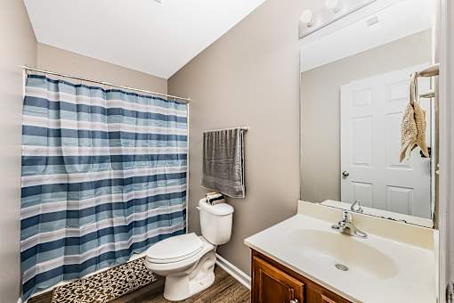 A bathroom with a toilet, sink, and shower curtain.