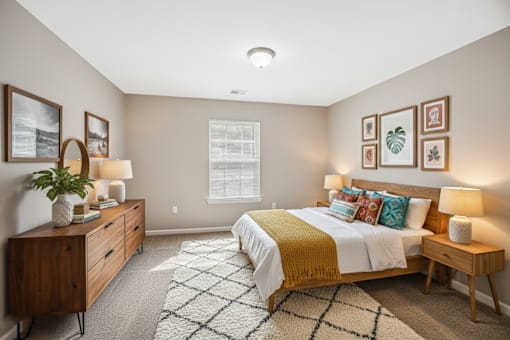 A bedroom with a bed, nightstands, and pictures on the wall.