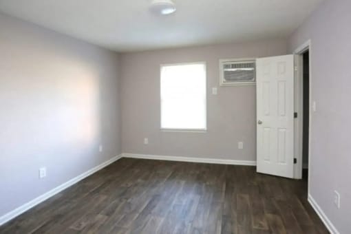 an empty living room with wood floors and a white door