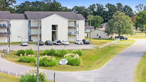 A view of a residential area with a building and cars parked in front.