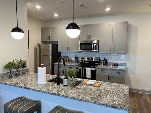 A kitchen with granite countertops and striped bar stools.