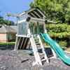 A green slide is attached to a wooden playhouse.