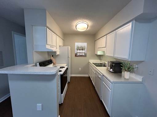 A kitchen with white cabinets and appliances.