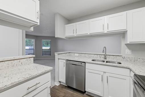 A kitchen with white cabinets and a granite countertop.