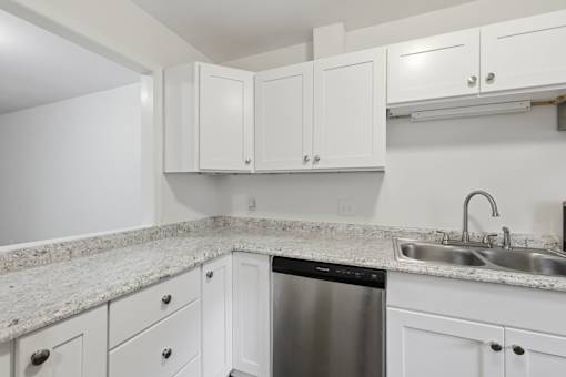 A kitchen with white cabinets and a granite countertop.