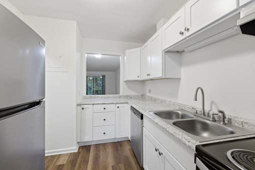 A kitchen with white cabinets and a stainless steel refrigerator.