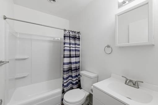 A white bathroom with a toilet, sink, and bathtub.
