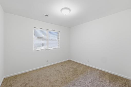 A room with a window and carpeted floor.