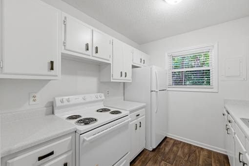 A white kitchen with a stove, oven, and refrigerator.