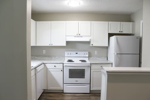 A white kitchen with a stove, oven, and refrigerator.