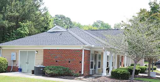 A small brick house with a grey roof and a white door.