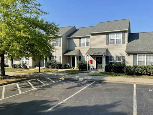 A parking lot in front of a building with a red door.