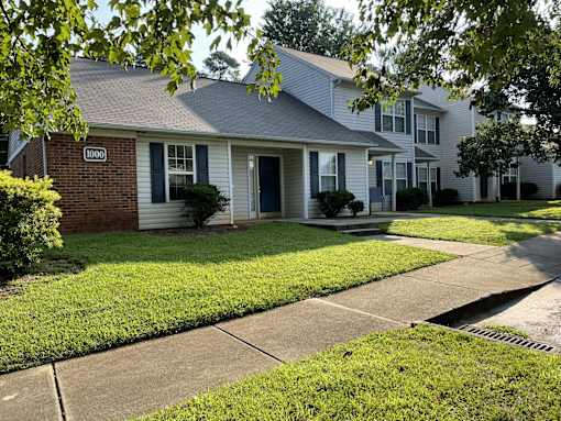 A house with a blue door and windows is surrounded by green grass.