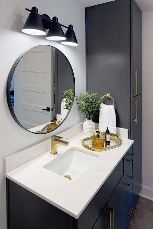 A bathroom with a white sink and a round mirror.
