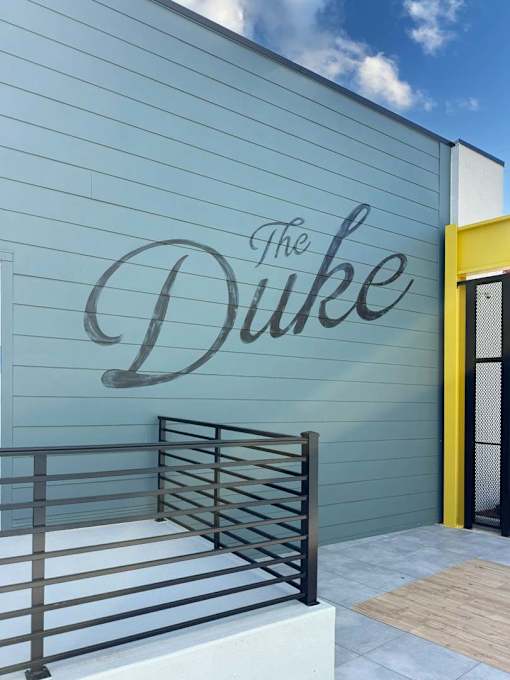 The Duke sign on a building with a yellow door.